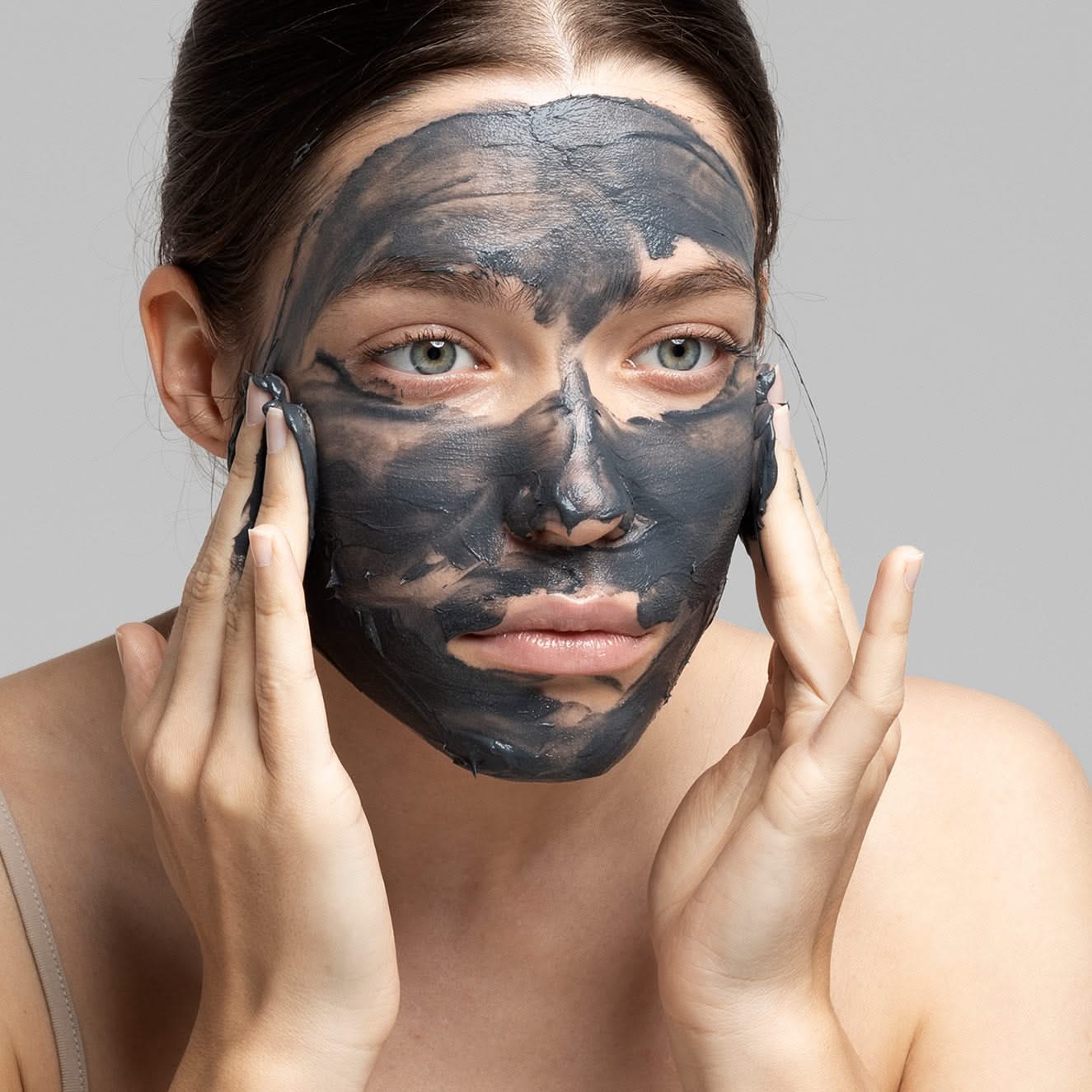 Frau trägt eine schwarze Gesichtsmaske und berührt ihr Gesicht mit den Händen.