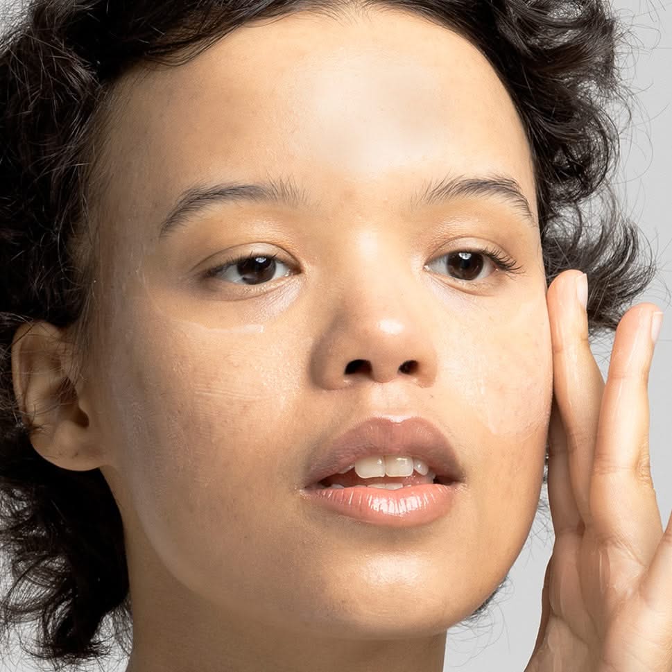 Eine Person mit feuchter Haut berührt ihr Gesicht mit der Hand.