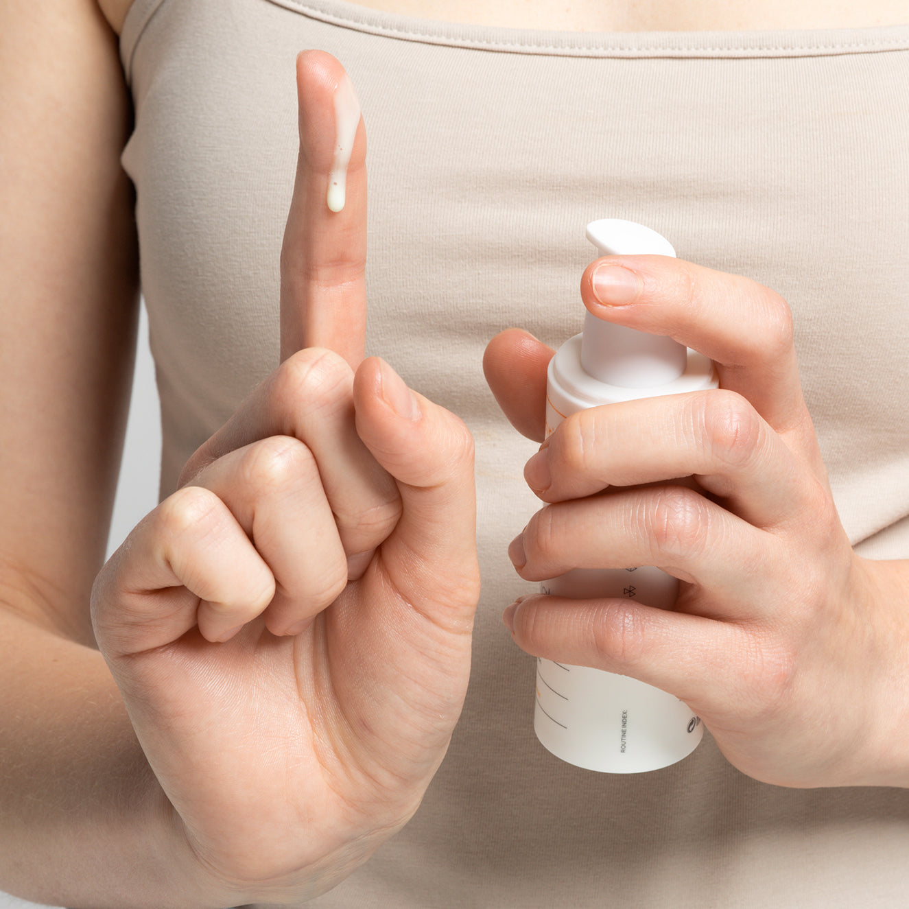 Person hält eine Flasche Lotion und trägt etwas davon auf einen Finger auf.