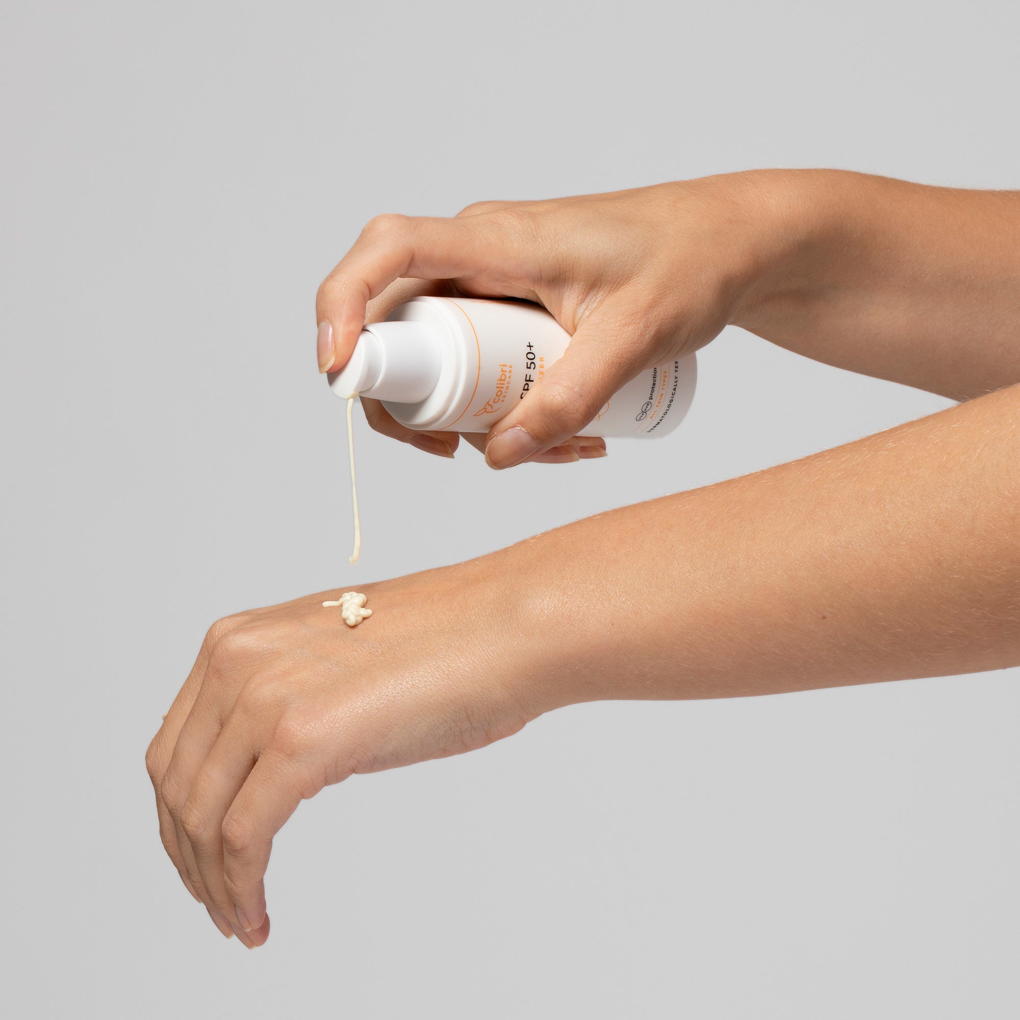 Eine Hand drückt Sonnencreme aus einem Spender auf den Handrücken einer anderen Hand.