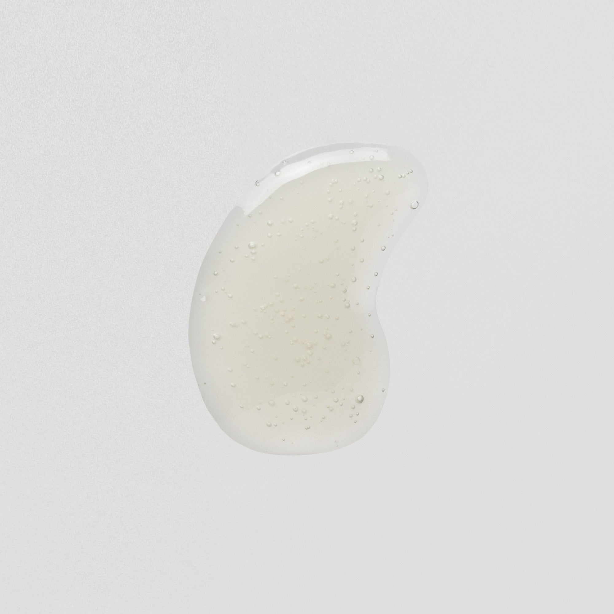 Transparenter Tropfen Gel mit kleinen Luftblasen auf weißem Hintergrund.
