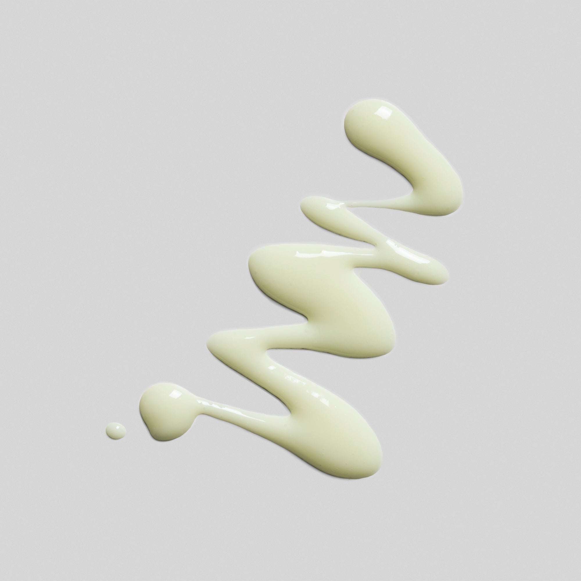 Gelbe Creme in einer wellenförmigen Linie auf grauem Hintergrund.