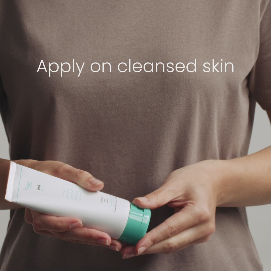 Eine Person hält eine Tube mit der Aufschrift "Apply on cleansed skin" auf einem braunen T-Shirt.